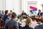 Ludzie siedzą przy stole. Za nimi widoczny baner z napisem Małopolska.