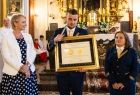 Przedstawiciele Amatorskiej Orkiestry Dętej Głębowice oraz Iwona Gibas z zarządu województwa prezentują wspólnie prestiżową nagrodę samorządu województwa małopolskiego