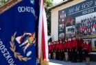 Na pierwszym planie sztandar OSP Broszkowice, w tle członkowie młodzieżowej drużyny pożarniczej