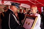 Iwona Gibas z zarządu województwa przekazuje Nagrodę Samorządu Województwa Złoty Medal Polonia Minor przyznaną z okazji 100-lecia OSP Broszkowice 