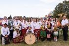 Muzycy z orkiestry dętej stoją na trawie z instrumentami.