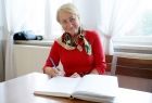 Iwona Gibas z zarządu województwa małopolskiego wpisująca się do księgi pamiątkowej