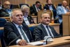 Radni województwa Grzegorz Biedroń i Rafał Stuglik siedzą w ławach sejmiku. Za nimi widoczni inni radni.
