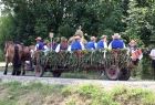 Ludzie w strojach ludowych jadą na wozie.