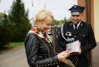 Członek zarządu województwa Iwona Gibas przeglądająca wydaną z okazji jubileuszu OSP Kęty książeczkę. Obok strażak ochotnik w galowym mundurze