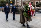 Marszałek Łukasz Smółka i dyrektor Dawid Gleń składają wieniec. Przed nimi idzie żołnierz.