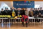 Uczestnicy spotkania stoją na sali. Nad nimi napis Małopolska.