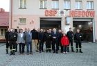 Uczestnicy wydarzenia stoją przed remizą z napisem OSP Hebdów.