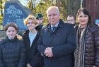 Wicemarszałek Ryszard Pagacz stoi z ludźmi. Za nimi widoczny pomnik.