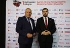 Wicemarszałek Ryszard Pagacz stoi z mężczyzną. Z tyłu widoczna ścianka.