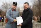 Arkadiusz Wrzoszczyk trzyma w rękach dokument. Obok stoi mężczyzna w historycznym mundurze.
