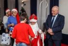 Wicemarszałek Ryszard Pagacz rozdaje dzieciom prezenty. Obok siedzi Święty Mikołaj.
