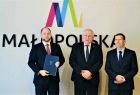 Wicemarszałek Ryszard Pagacz stoi z dwoma mężczyznami. Za nimi na ścianie widoczne logo Małopolska.