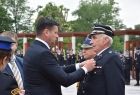 Wicemarszałek Łukasz Smółka przypina medal strażakowi. 