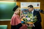 Wicemarszałek Łukasz Smółka wręcza kwiaty kobiecie.