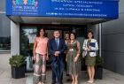 Wicemarszałek Witold Kozłowski stoi przed wejściem do szpitala. Obok stoją trzy kobiety.