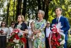 Iwona Gibas z zarządu województwa, Teresa Jankowska wicestarosta powiatu oświęcimskiego oraz Łukasz Kobielusz zastępca burmistrza Brzeszcz stojący z kwiatami przed pomnikiem upamiętniającym ofiary podobozu KL Auschwitz - Jawischowitz