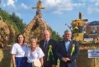 Wicemarszałek Ryszard Pagacz stoi przed wieńcami dożynkowymi. Obok stoją inny ludzie.
