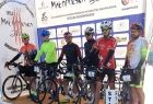 Kolarze z rowerami stoją na podium.