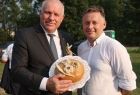 Wicemarszałek Ryszard Pagacz trzyma w rękach bochen chleba. Obok stoi mężczyzna z białej koszuli.