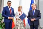 Kobieta trzymająca teczkę w rękach z członkami zarządu.