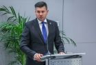 Marszałek Łukasz Smółka mówi przy mównicy na scenie do mikrofonu.