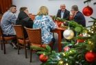 Grupa osób siedząca przy stole. Na pierwszym planie choinka.