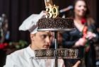 zbliżenie - widok na tort okolicznościowy z okazji 39 urodzin Teatru Witkacy - fotografia tortu na tle cukiernika stojącego z tyłu