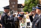 Wicemarszałek Łukasz Smółka salutujący przed strażakiem.
