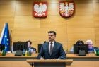 Marszałek Łukasz Smółka stoi przy mównicy.