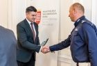Marszałek Łukasz Smółka podaje rękę policjantowi.