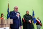 Wicemarszałek Ryszard Pagacz trzyma w ręce mikrofon. Obok stoi ksiądz.