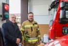 Wicemarszałek Ryszard Pagacz ogląda wóz strażacki w towarzystwie strażaka.