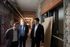 Wicemarszałek Łukasz Smółka idzie remontowanym korytarzem szpitalnych w towarzystwie innych ludzi.