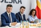 Marszałek Łukasz Smółka siedzi przy stole z innymi ludźmi.