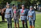 Żołnierze w strojach historycznych stoją na trawie.