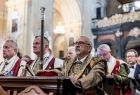 Uczestnicy mszy świętej, siedzący w kościelnych ławach w ozdobnych, historycznych strojach