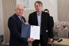 Wicemarszałek Ryszard Gawron stoi z mężczyzną. W rękach trzyma dokument.