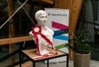 Białe popiersie z biało-czerwonym kotylionem. 