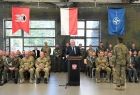 Wicemarszałek Ryszard Pagacz stoi przy mównicy. Obok siedzą żołnierze. Na górze widoczne flagi Polski i NATO.
