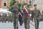 Uczniowie w mundurach idą przez rynek.