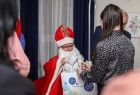 Święty Mikołaj rozdaje dzieciom prezenty.