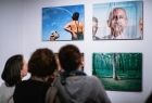 Troje ludzi ogląda zdjęcia powieszone na ścianie w galerii.