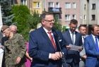 Mężczyzna przemawia. Za nim stoją inni ludzie.