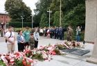 Grupa mieszkańców wraz małym chłopcem w wojskowym mundurze przed Grobem Nieznanego Żołnierza w Oświęcimiu 