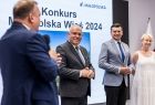 Mężczyzna z mikrofonem stoi na scenie.