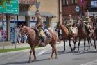 Żołnierze na koniach jadą ulicą.