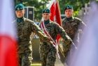 Żołnierze maszerują wśród polskich flag.