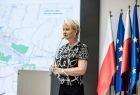 Iwona Gibas z zarządu województwa stoi przy mównicy. Za nim widoczne flagi.