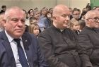 Wicemarszałek Ryszard Pagacz siedzi na widowni. Obok siedzą księża.